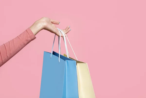 Comprador y adicto a las compras, tiempo libre activo. Mano de mujer afroamericana sosteniendo bolsas azules y amarillas —  Fotos de Stock