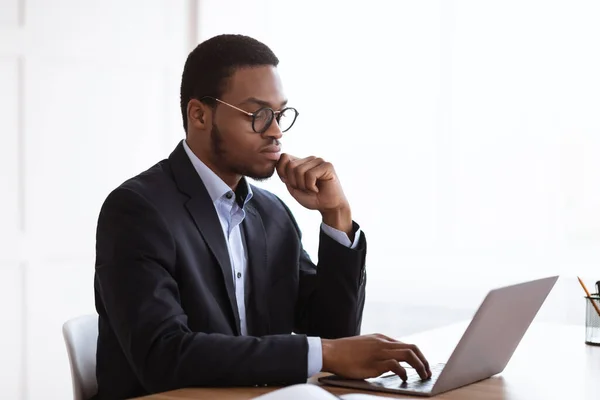 Gerente afroamericano serio que trabaja con el ordenador portátil en la oficina —  Fotos de Stock