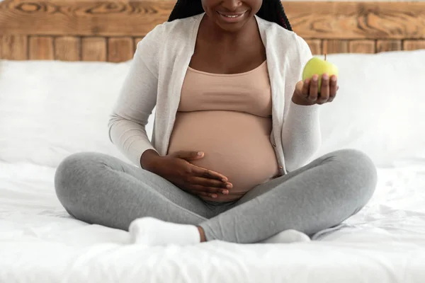 Dieta przedporodowa. Czarna kobieta w ciąży trzymając zielone jabłko i dotykając brzucha, przycięte — Zdjęcie stockowe