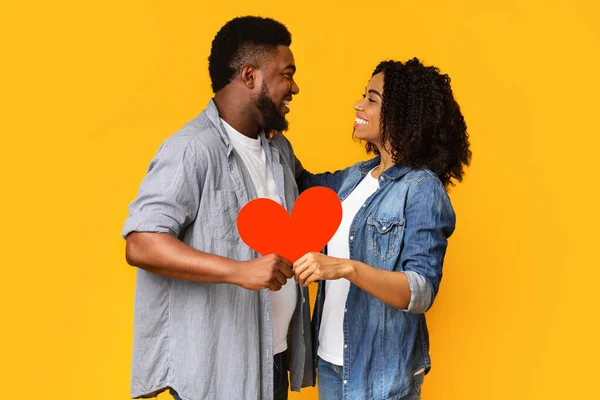 Todo lo que necesitas es amor. Feliz pareja negra sosteniendo un gran corazón rojo — Foto de Stock