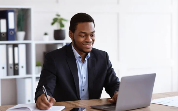 Hombre de negocios negro alegre escuchando webinar, interior de la oficina —  Fotos de Stock