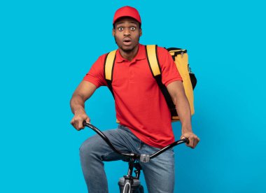 Komik zenci teslimatçı stüdyoda bisiklete biniyor.