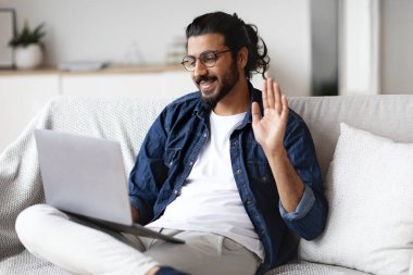 Çevrimiçi İletişim. Evde dizüstü bilgisayarla video görüşmesi yapan pozitif doğulu adam.
