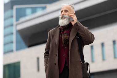 Zengin kıdemli bir adam dışarıda telefonla konuşuyor.