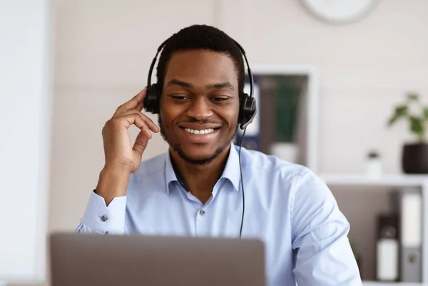 Primer plano del trabajador negro con auriculares usando el ordenador portátil, interior de la oficina —  Fotos de Stock