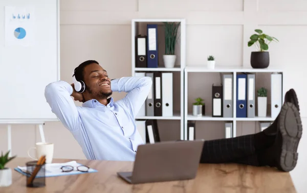 Vreedzame zwarte manager luistert naar muziek in zijn kantoor — Stockfoto