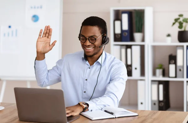 Χαρούμενος μαύρος σύμβουλος με ακουστικά που χαιρετάει στην οθόνη laptop — Φωτογραφία Αρχείου