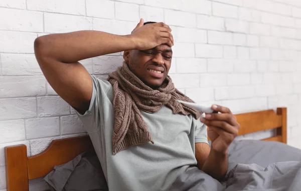 Ill zwarte man met koorts zittend in bed binnen — Stockfoto
