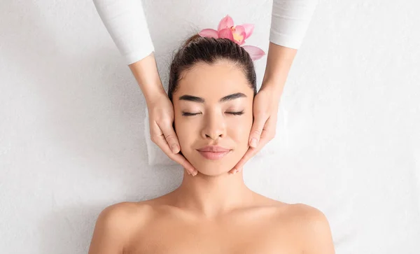 Fiatal ázsiai nő élvezi bőrfelemelő arcmasszázs wellness központban — Stock Fotó