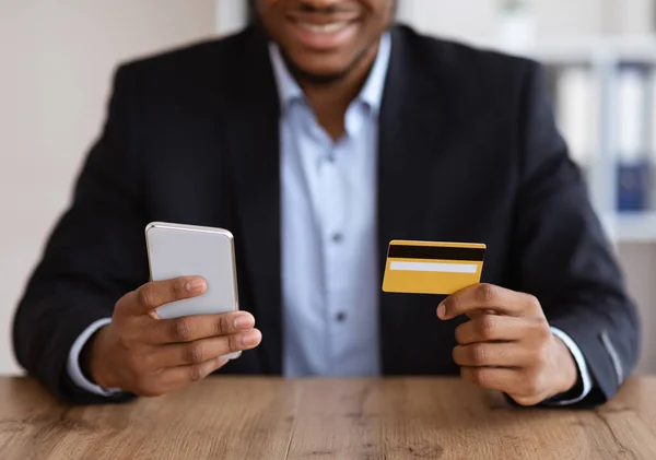 Czarny mężczyzna w garniturze z telefonem komórkowym i kartą kredytową — Zdjęcie stockowe