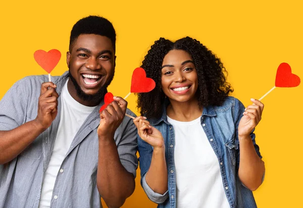 Merayakan Hari Valentine. Pasangan kulit hitam memegang hati kertas merah pada tongkat — Stok Foto