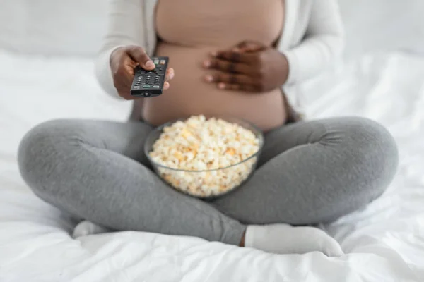 Oříznutý záběr těhotné ženy s popcornem a dálkovým ovladačem v rukou — Stock fotografie