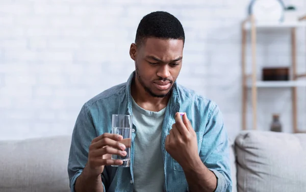 Sick African Man Holding Pill And Water Sitting At Home — Stock Photo, Image