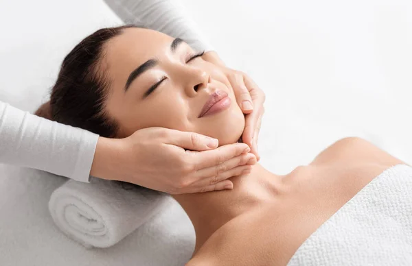 Massagem facial. Closeup de atraente mulher asiática recebendo tratamento de beleza no spa — Fotografia de Stock