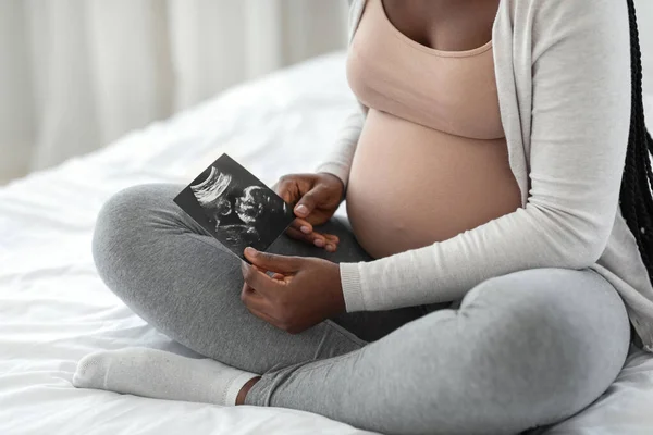 Desarrollo fetal. Mujer africana embarazada mirando ultrasonido de bebé en casa — Foto de Stock