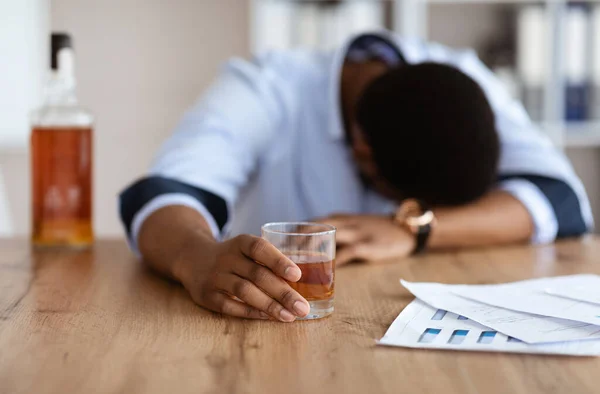 Американский бизнесмен, страдающий стрессом, пьющий виски на рабочем месте — стоковое фото