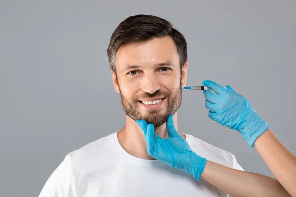 Nierozpoznawalny kosmetyk wstrzykujący wypełniacz do twarzy dla mężczyzny w średnim wieku — Zdjęcie stockowe