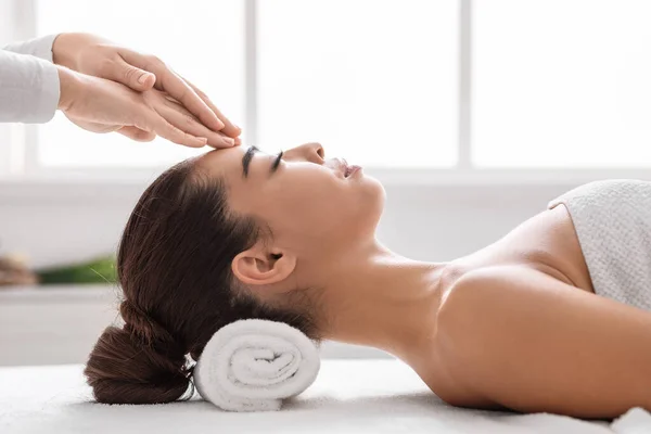 Mulher asiática bonita no salão de spa desfrutando de massagem na cabeça acupressão, vista lateral — Fotografia de Stock