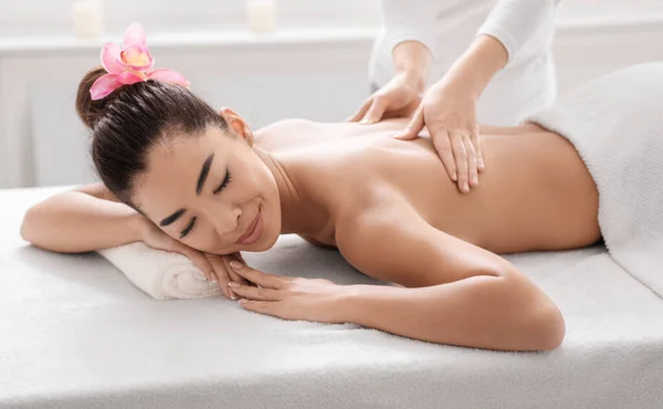 Mulher asiática desfrutando de massagem nas costas no salão de Spa, recebendo tratamento de beleza relaxante — Fotografia de Stock