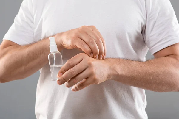 Onherkenbare man die spray vasthoudt en aan zijn hand krabt. — Stockfoto