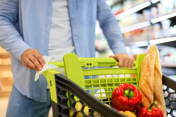 Alışveriş arabasının sapını temizleyen tanınmamış genç adam.