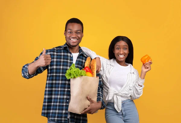 Gesunde Ernährung, moderne Online-Bestellung von Produkten. Glückliche junge afrikanisch-amerikanische Mann und Frau halten Papiertüten — Stockfoto