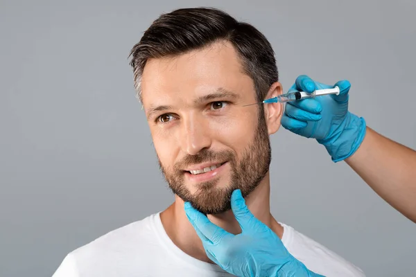 Handsome man getting under eye injections, grey background, empty space — Stock Photo, Image