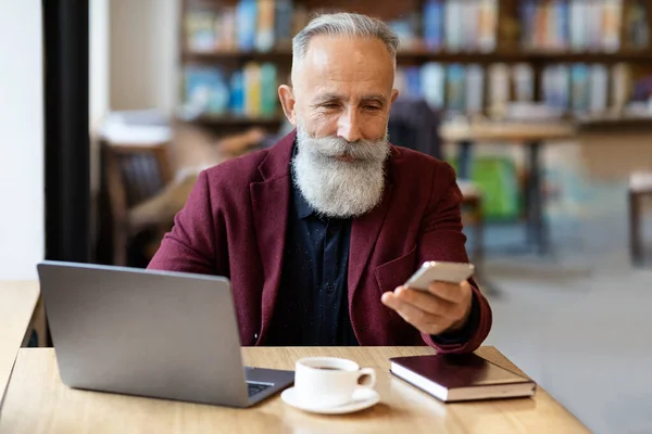 Akıllı telefonlu zengin bir girişimci dizüstü bilgisayarın önünde oturuyor. — Stok fotoğraf