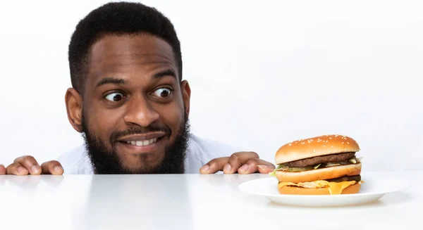 Engraçado com fome preto homem olhando para hambúrguer sobre fundo branco — Fotografia de Stock