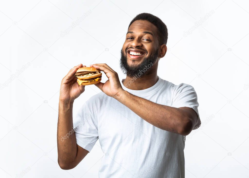 Smiling Black Guy Holding Unhealthy Burger, Studio Shot