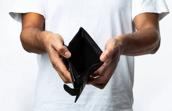 Nerozpoznatelný černoch ukazující prázdnou peněženku stojící nad bílým pozadím — Stock fotografie