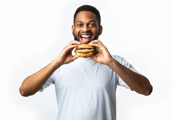 African Guy Biss Burger Essen ungesundes Junk Food, weißer Hintergrund — Stockfoto