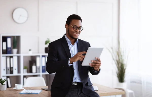 Szczęśliwy afrykański młody biznesmen za pomocą tabletu cyfrowego w biurze — Zdjęcie stockowe