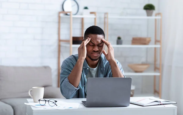 Afro-Amerikalı iş adamı bilgisayarın başında otururken baş ağrısı çekiyor. — Stok fotoğraf