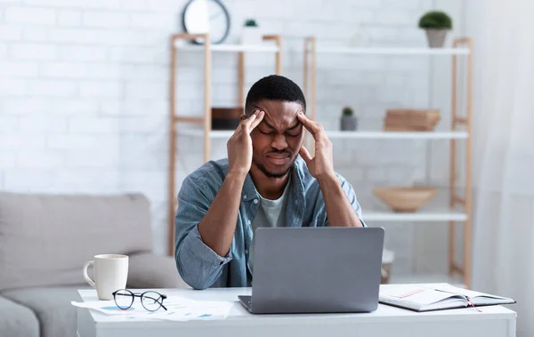 Hombre de negocios afroamericano con dolor de cabeza sentado en el portátil interior — Foto de Stock