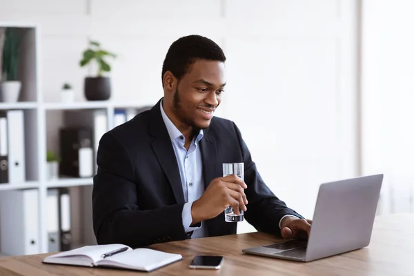 Smiling black manager reading sales report on laptop — Stock Photo, Image