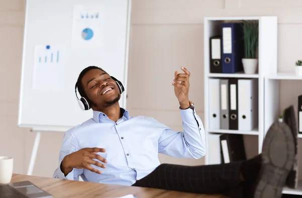 Relajado afroamericano hombre escuchando música durante el día de trabajo —  Fotos de Stock