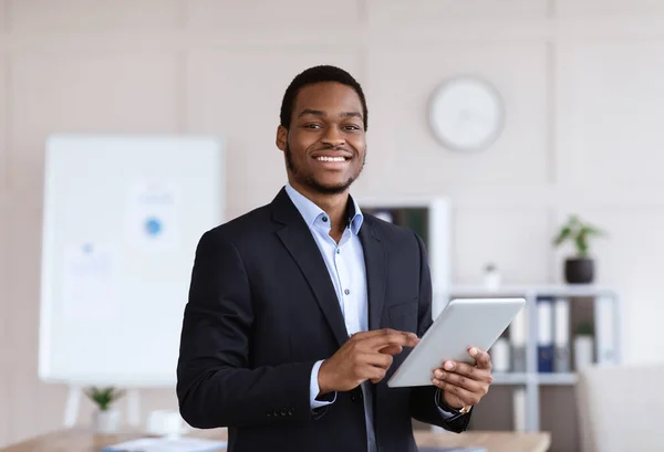 Sonriente empresario negro sosteniendo tableta digital, interior de la oficina —  Fotos de Stock