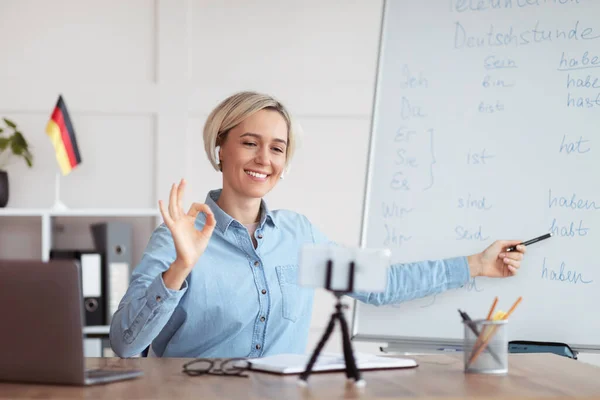 Online foreign languages school. Young female tutor conducting German lesson on web, showing okay gesture — Stock Photo, Image