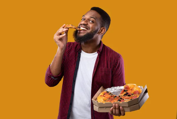 Engraçado preto homem comer pizza sobre amarelo estúdio fundo — Fotografia de Stock