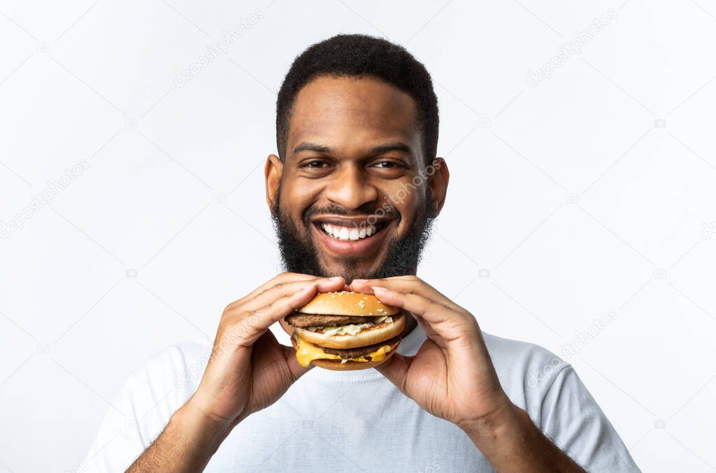 Cheerful African Man Holding Burger Smiling To Camera, White Background