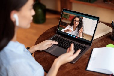 Omuz üstünden öğretmenle çevrimiçi ders alan bir kadın.