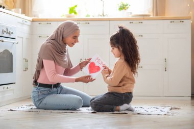 Anneler Günün kutlu olsun. Küçük kız müslüman annesini hediye kartıyla selamlıyor.