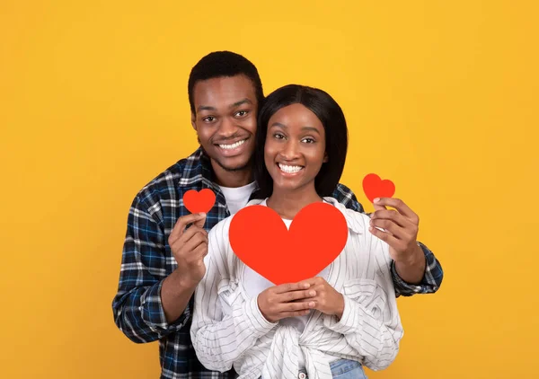 Felices fiestas, romance, aniversario y amor. Feliz afroamericano chico y señora sosteniendo corazones rojos — Foto de Stock