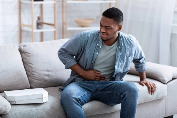 Chico afroamericano teniendo dolor de estómago después de comer pizza en casa — Foto de Stock