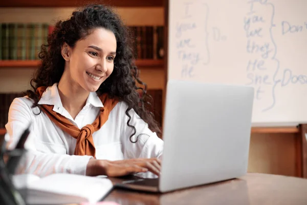 Junge Frau sitzt am Schreibtisch, benutzt Computer und tippt — Stockfoto