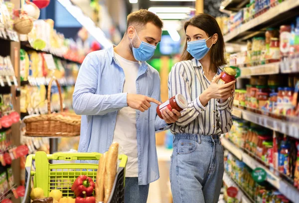 Jong stel in wegwerp gezichtsmaskers winkelen in supermarkt — Stockfoto