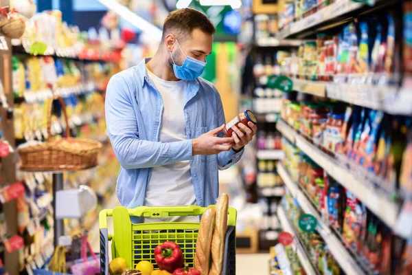 Young guy in medical mask with cart shopping in market