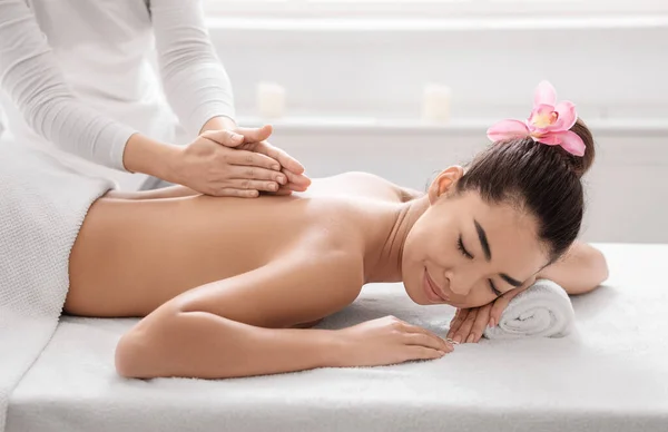 Vacker asiatisk kvinna ligger på spa säng, få tillbaka massage behandling — Stockfoto