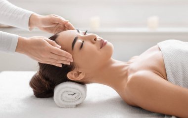 Sakin, genç Asyalı bayan güzellik salonunda yüz masajı yapıyor.